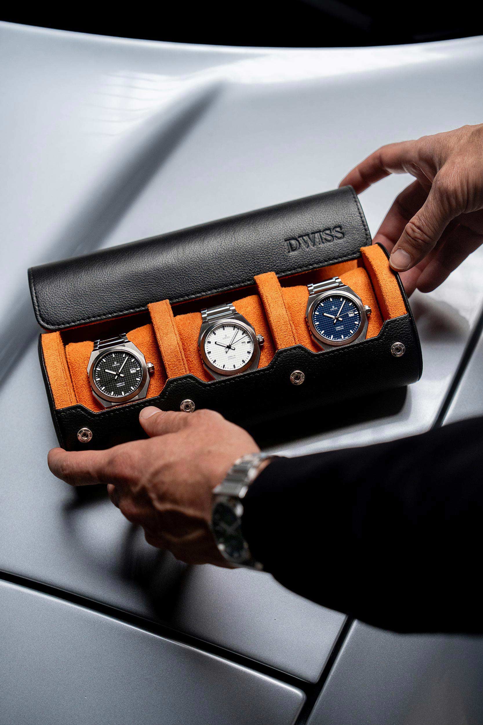 Three DWISS A1 watches in a black and orange display case held by a person against a Honda NSX car.
DWISS A1 model using Movement: Swiss made automatic movement La Joux-Perret G100 Soigné
The fourth watch of the collection on the wrist.