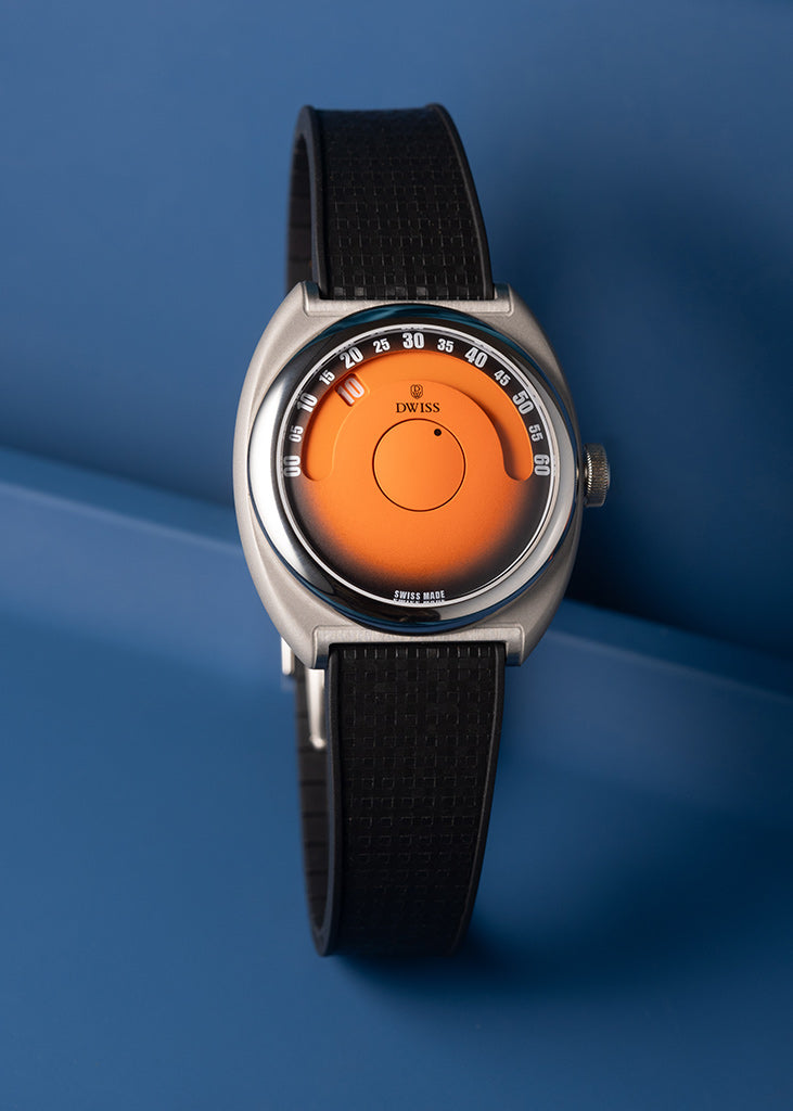 DWISS S1 Wandering Hours Naranja con esfera de fume gradiente negro. Un reloj de pulsera con una correa de textura negra, una caja de plata y un dial circular naranja distintivo, fotografiado contra un fondo azul.