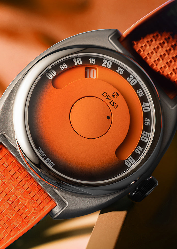 DWISS S1 Wandering Horas Naranja con esfera de fume gradiente negro. Cierre de un reloj de pulsera Swiss Made con una caja gris oscura, un dial de color naranja brillante y una correa de textura naranja contra un fondo borroso cálido.