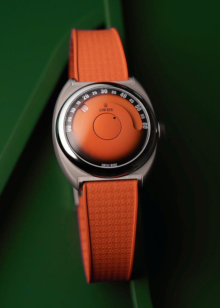 DWISS S1 Wandering Hours Naranja con esfera de fume gradiente negro, un reloj de pulsera con una correa de color naranja texturada y un dial de color naranja coincidente, con una caja redonda de plata y un bisel exterior negro con marcas blancas, situado en un fondo verde oscuro.
