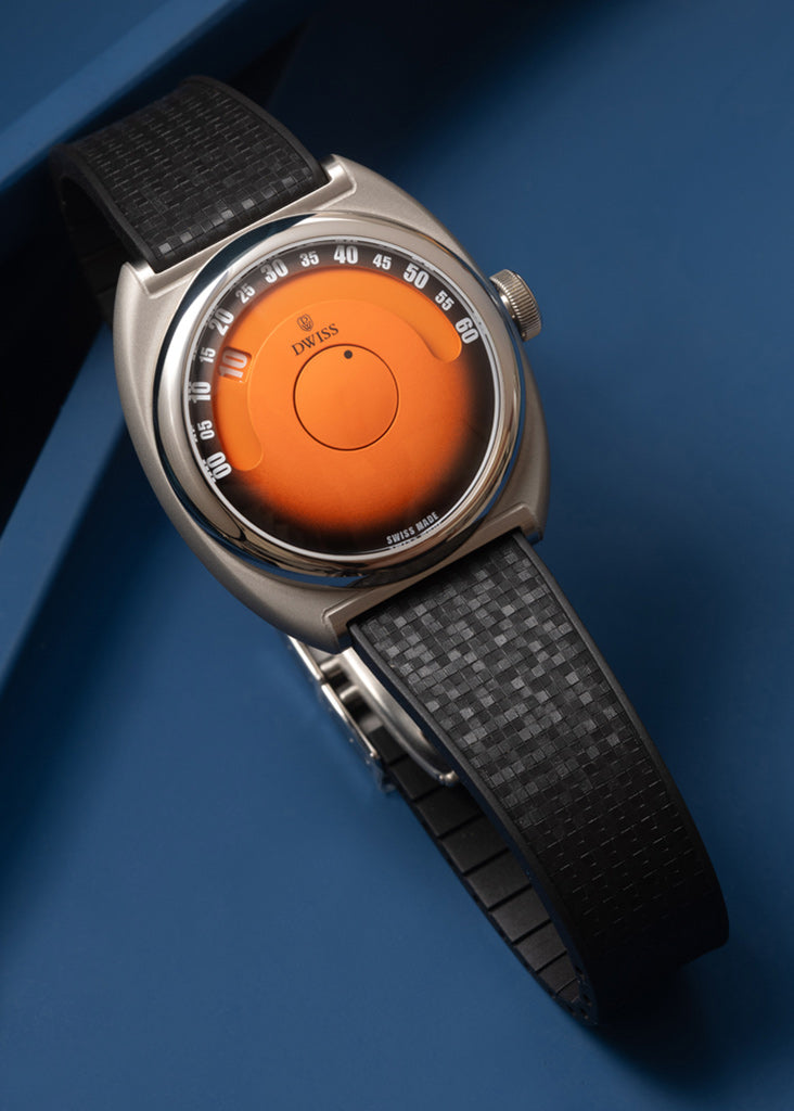 DWISS S1 Wandering Hours Naranja con esfera de fume gradiente negro. Un reloj de pulsera con una caja ovalada de plata, una esfera naranja brillante y una correa de textura negra, fotografiada en un fondo azul.