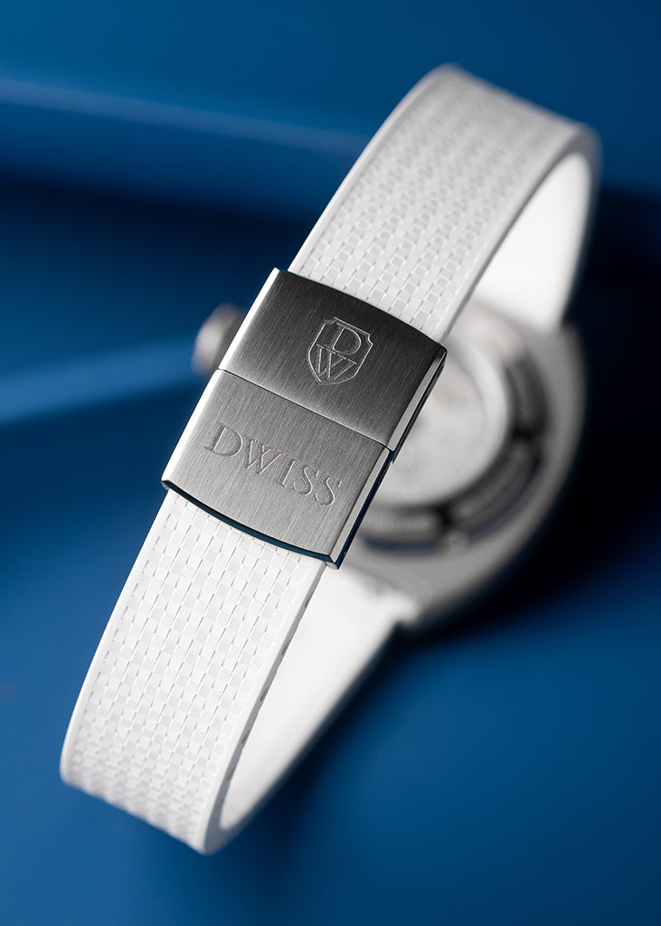 Un cierre de una correa de reloj de textura blanca con un cepillado de plata m eta l clasp grabado con el logotipo suizo y la palabra ' DWISS', con un fondo azul oscuro. DWISS S1 Wandering Horas dial circular cepillado.